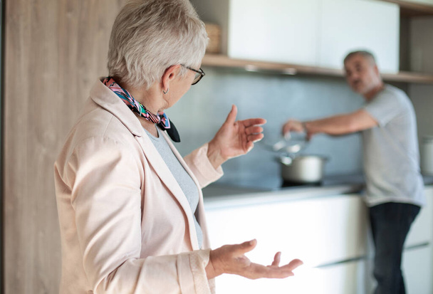 friendly old lady talking standing in the kitchen . - Фото, зображення