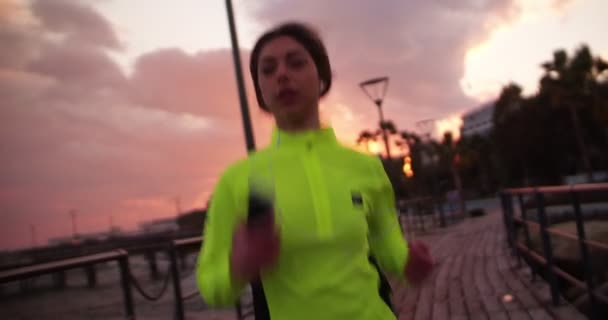 Fit woman jogging and listening to music on her smartphone - Video, Çekim