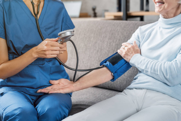 Image recadrée de l'assistante médicale mesurant la pression artérielle féminine
 - Photo, image