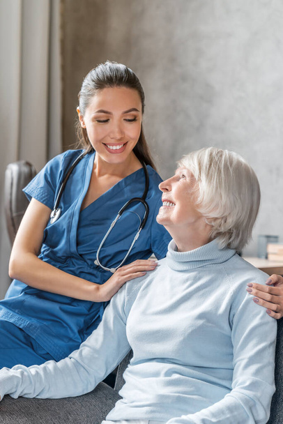 Vertical portrait of happy elderly woman with nurse at home - Foto, Imagem