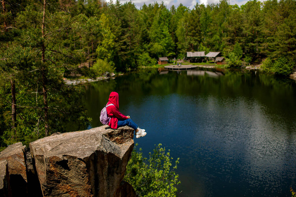 Jeune femme asiatique adulte avec un sac à dos sur un rocher admirant la vue sur un lac en automne. - Photo, image