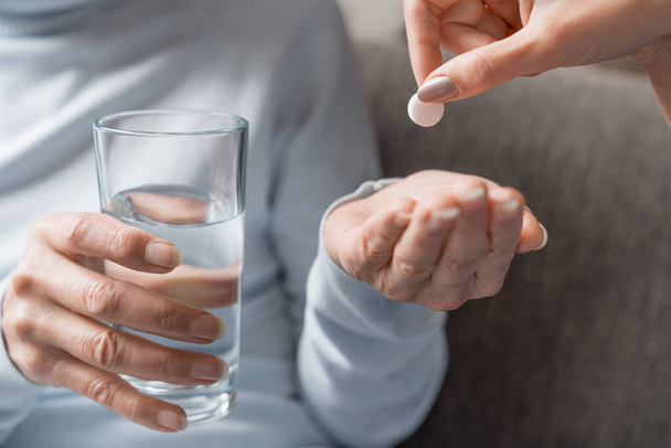 Caring nurse giving pills to senior woman with glass of water in hand - Photo, Image