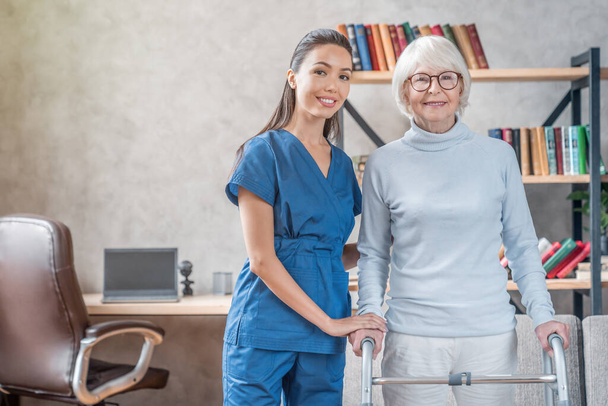 Portrait of senior woman and supporting nurse at home - Foto, Imagem