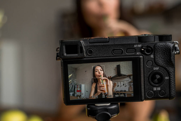 close-up van camera scherm tonen vrouw drinken vers sap aan keukentafel - Foto, afbeelding