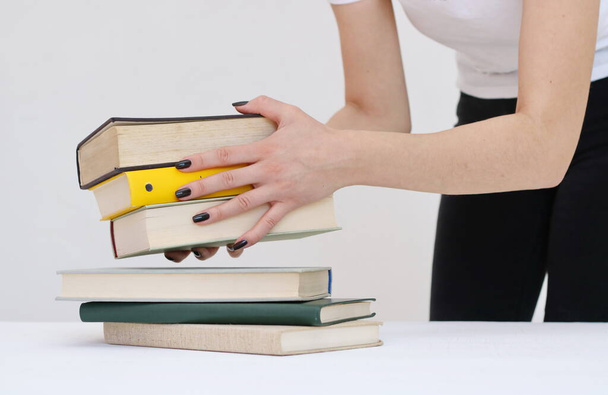 Μια όμορφη νεαρή μαθήτρια κρατά βιβλία στα χέρια της. - Φωτογραφία, εικόνα