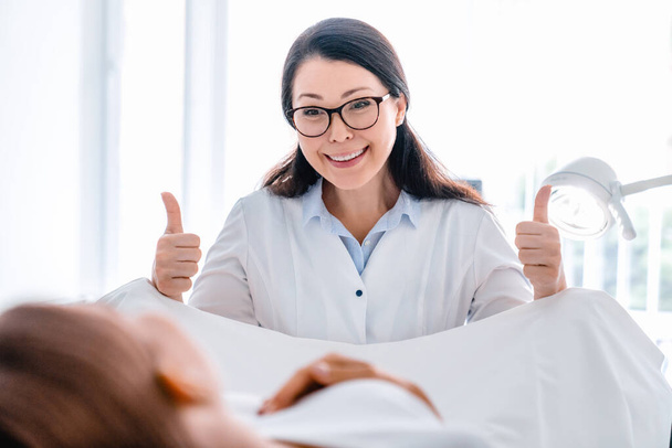 Smiling mid adult gynecologist examines a woman in modern clinic - Фото, изображение