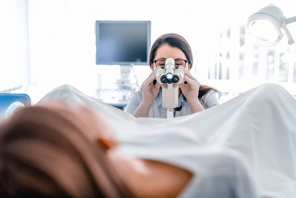 Adult woman gynecologist examining patient in hospital using colposcope - Valokuva, kuva