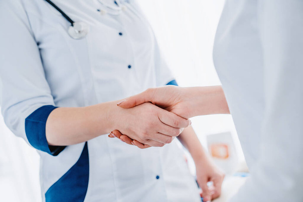 Close up of woman doctor shaking hands with patient - 写真・画像