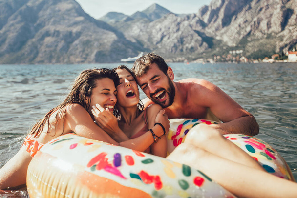 Les jeunes gens à la mode s'amusent à nager pendant les vacances d'été, se détendre sur l'anneau gonflable
. - Photo, image