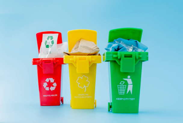 Yellow, green and red recycle bins with recycle symbol on blue background. Keep city tidy, Leaves the recycling symbol. Nature protection concept - Photo, image