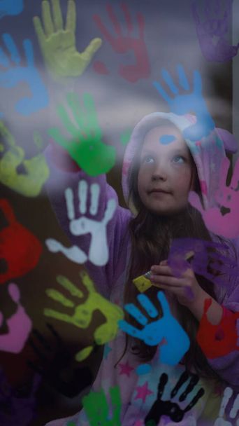 μαθήτρια με πιτζάμες ζωγραφισμένη με παλάμες στο παράθυρο. - Φωτογραφία, εικόνα