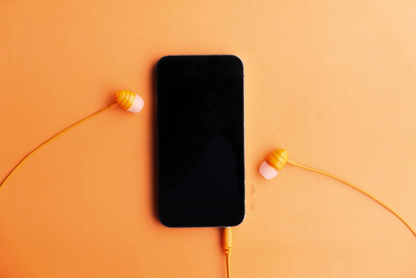 smart phone and earphone on orange background . - Photo, Image