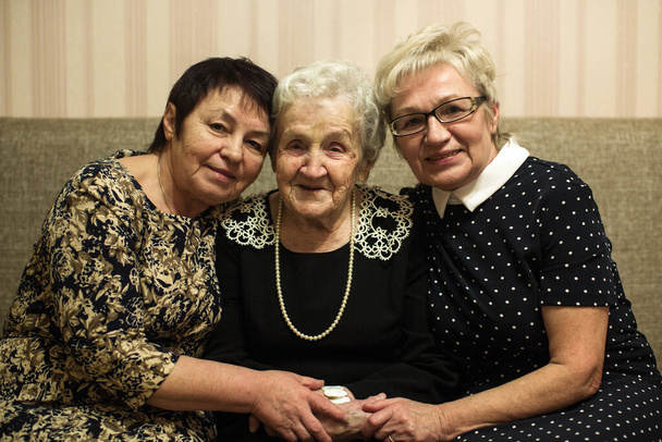 An old woman with two adult daughters sitting and posing on a sofa. - Photo, Image