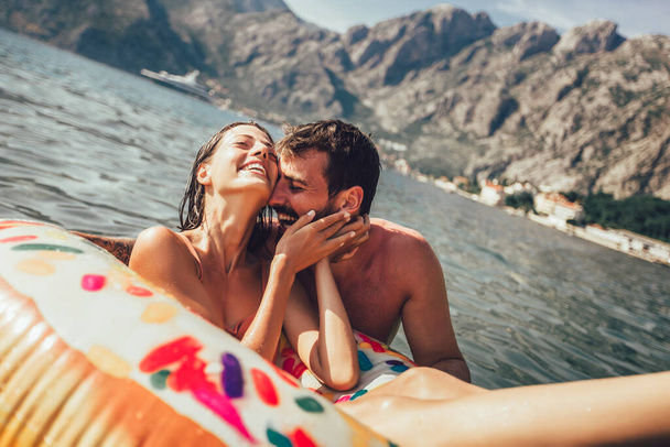 Молодая модная пара с удовольствием купается на летних каникулах, расслабляется на надувном кольце
. - Фото, изображение