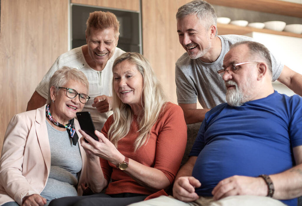 Mature woman showing friends photos on her smartphone. - Foto, Bild