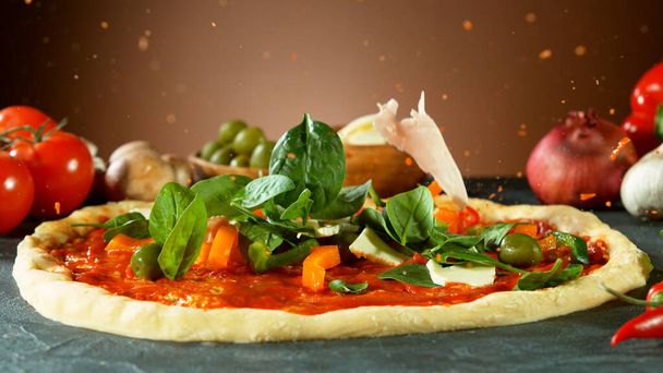 Falling raw ingredients on pizza, freeze motion. Italian traditional meal. - Foto, Imagen