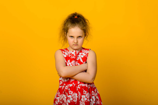 Angry little girl isolated on a over yellow background - Фото, изображение