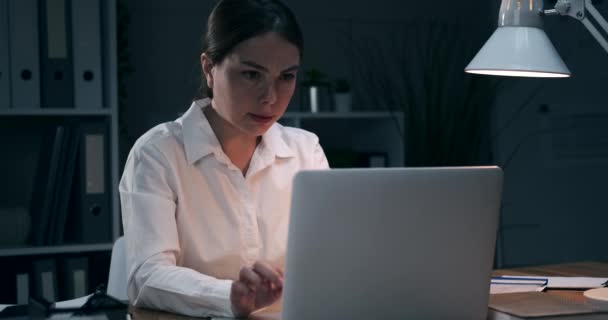Empresaria recibiendo malas noticias en el ordenador portátil en la oficina de noche
 - Imágenes, Vídeo