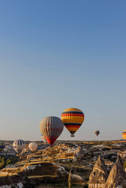 Goreme, Cappadocia, Turkey 23 August 2019: Many hot air balloons in sky. People look at them from the ground. Cappadocia Earth Pyramids. Tourism concept. - Foto, Imagen
