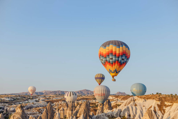 Goreme, Capadocia, Turquía 23 de agosto de 2019: Muchos globos aerostáticos en el cielo. La gente los mira desde el suelo. Capadocia Earth Pyramids. Concepto turístico
. - Foto, imagen