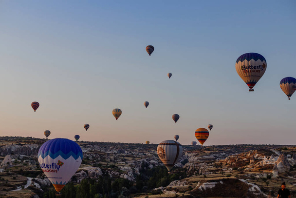 Goreme, Cappadocia, Turkey 23 August 2019: Many hot air balloons in sky. People look at them from the ground. Cappadocia Earth Pyramids. Tourism concept. - Φωτογραφία, εικόνα