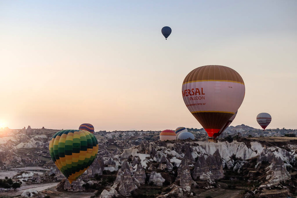 Goreme, Kapadocja, Turcja 23. sierpnia 2019: Wiele balonów na ogrzane powietrze na niebie. Ludzie patrzą na nie z ziemi. Ziemskie piramidy Kapadocji. Koncepcja turystyki. - Zdjęcie, obraz