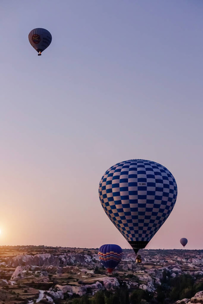 Goreme, Cappadocia, Turkey 23 August 2019: Many hot air balloons in sky. People look at them from the ground. Cappadocia Earth Pyramids. Tourism concept. - Foto, imagen