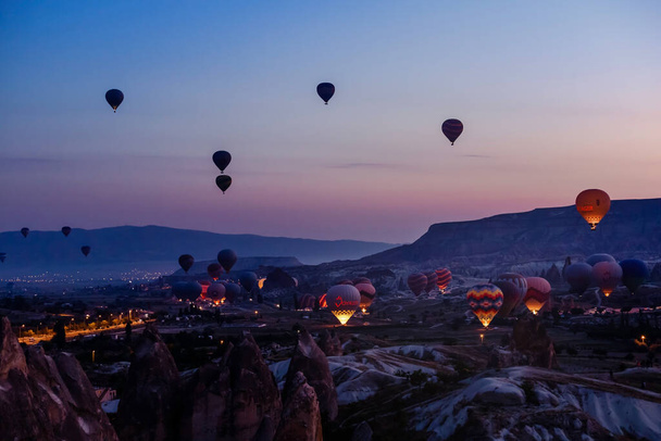 Goreme, Cappadocia, Turkey 23 August 2019: Many hot air balloons in sky. People look at them from the ground. Cappadocia Earth Pyramids. Tourism concept. - Zdjęcie, obraz