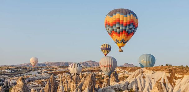 Goreme, Cappadocia, Törökország 23 augusztus 2019: Sok hőlégballon az égen. Az emberek a földről nézik őket. Kappadocia Földi Piramisok. Turisztikai koncepció. - Fotó, kép