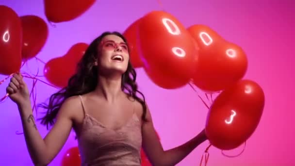 Joyful woman with heart shaped balls dancing. - Video