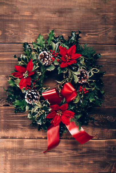 Amazing Christmas wreath with big red bow on wooden background - Foto, afbeelding