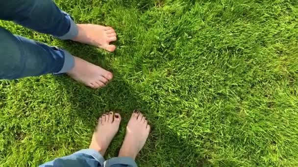The bare feet of girls in jeans are dancing happily on the green grass POV. Concept of freedom and happiness. Feet with pedicure. Loop boomerang animation for instagram story. Vertical Video - Footage, Video