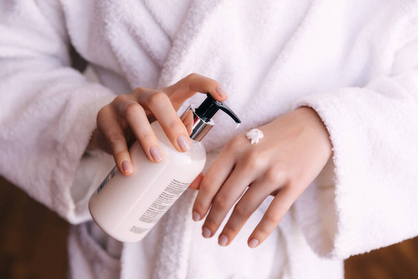 mains de femme appliquant de la crème hydratante sur sa peau - Photo, image