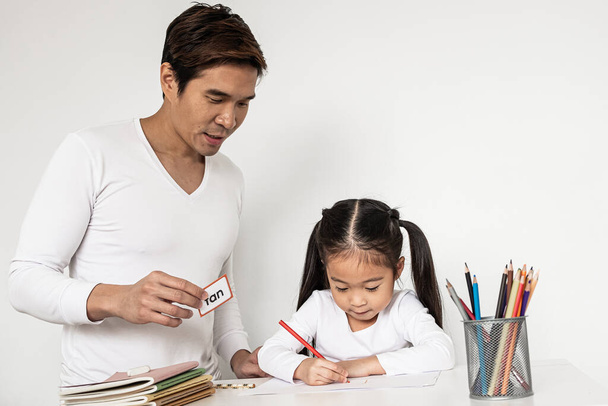 Jeune père asiatique aidant sa fille avec son projet scolaire à la maison, enfants étudiant à la maison
 - Photo, image