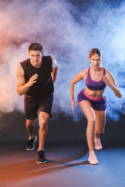 Sporty running young couple on dark background - Fotó, kép