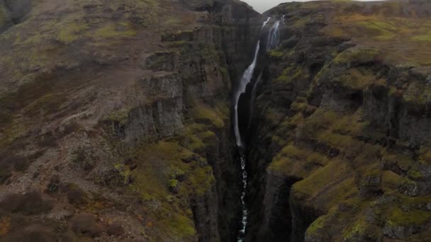 Aerial of rocky green Fjadrargljufur Canyon in Iceland with a stream waterfall - Imágenes, Vídeo