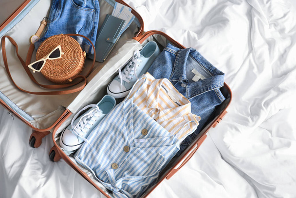 Open packed suitcase on bed - Photo, Image