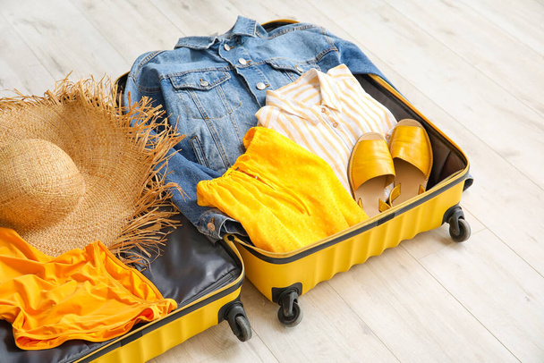 Open packed suitcase on wooden background - Photo, Image