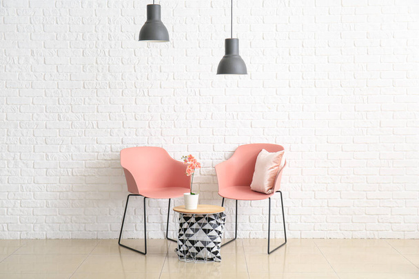 Εσωτερικό του σύγχρονου σαλονιού με καρέκλες και τραπέζι κοντά σε λευκό τοίχο από τούβλα - Φωτογραφία, εικόνα