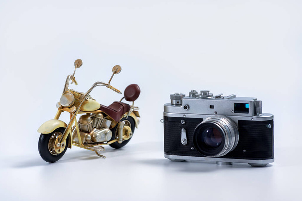 Turystyka i koncepcja podróży - zabytkowy aparat fotograficzny i cynowy model motocykla vintage na białym tle  - Zdjęcie, obraz