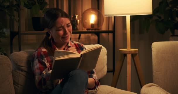 Ευαίσθητη γυναίκα κλαίει ενώ διαβάζει το βιβλίο στο σπίτι - Πλάνα, βίντεο