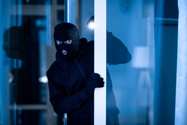 Ladrón irrumpiendo en el apartamento para robar, usando la antorcha
 - Foto, Imagen