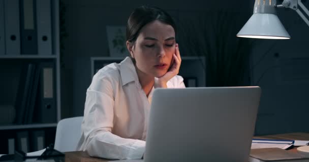 Empresaria bostezando y trabajando horas extras en la oficina nocturna
 - Imágenes, Vídeo