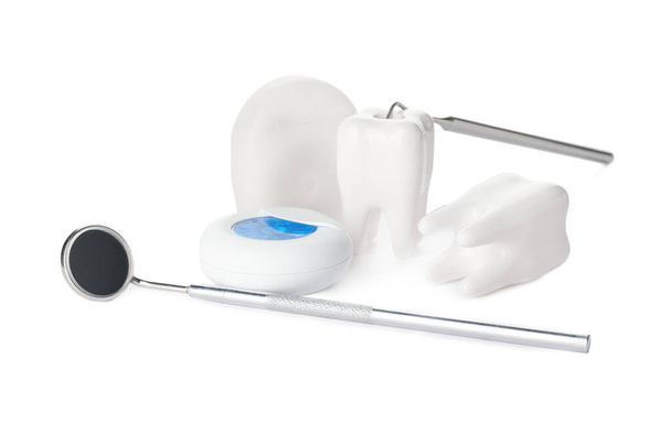 Dentes com ferramentas dentárias e fio dental sobre fundo branco
 - Foto, Imagem