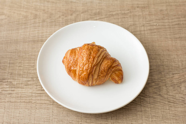 Food plate with croissant Dish showing bun of pastry. On rustic wooden table. - Foto, immagini