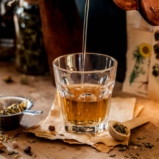 Pouring Herbal Tea into a Glass, Variety of Dried Herb Mixes, square - Фото, изображение