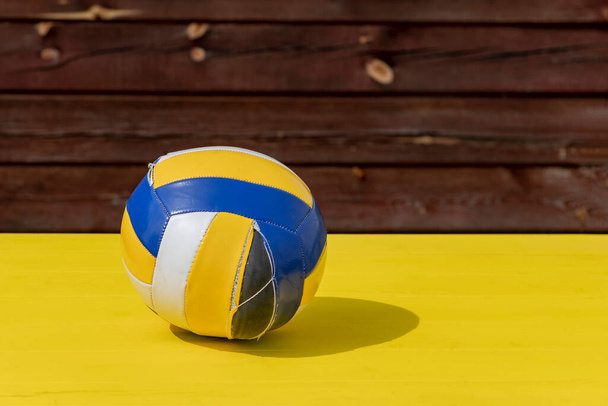 luz del día. sol muy brillante. Fondo de madera amarillo retro. La pelota de voleibol se rompió por completo
. - Foto, Imagen