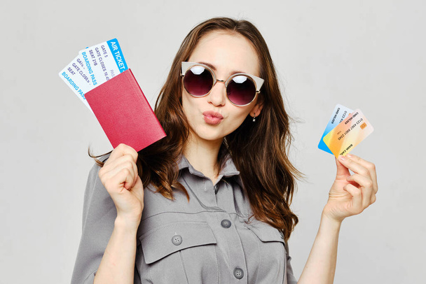 Chica alegre con gafas con billetes de avión y tarjetas bancarias de crédito
 - Foto, imagen
