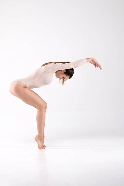 Γυναίκα χορεύτρια σε χορευτική ποζάρει στο πάτωμα των δακτύλων σε λευκό φόντο. Τέχνη, στυλ, φόντο, όμορφο, ασυνήθιστο, σύγχρονο. - Φωτογραφία, εικόνα
