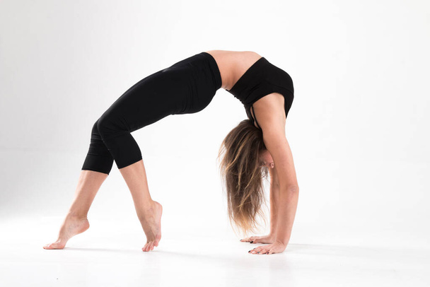 Girl in gymnastic bridge poses on a white background. Flexibility, strength, modern, stretching, classic, elegant, style, exercise, workout, beautiful, elastic, athlete - Фото, зображення